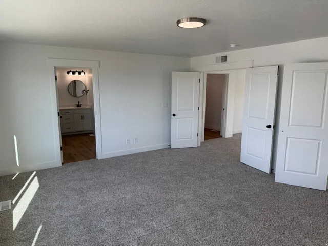 Spacious room featuring plush gray carpeting, white walls, and a contemporary ceiling light fixture