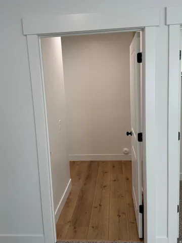 Entryway featuring wood-finish flooring, white baseboards, and a white interior door with matte black hardware