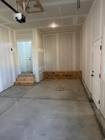 Spacious garage featuring a concrete floor, an overhead garage door opener, an interior access door, and a utility access panel