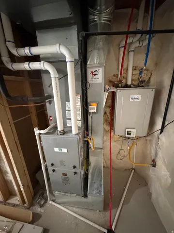 Utility area featuring a furnace unit, water heater, visible ductwork, and plumbing lines