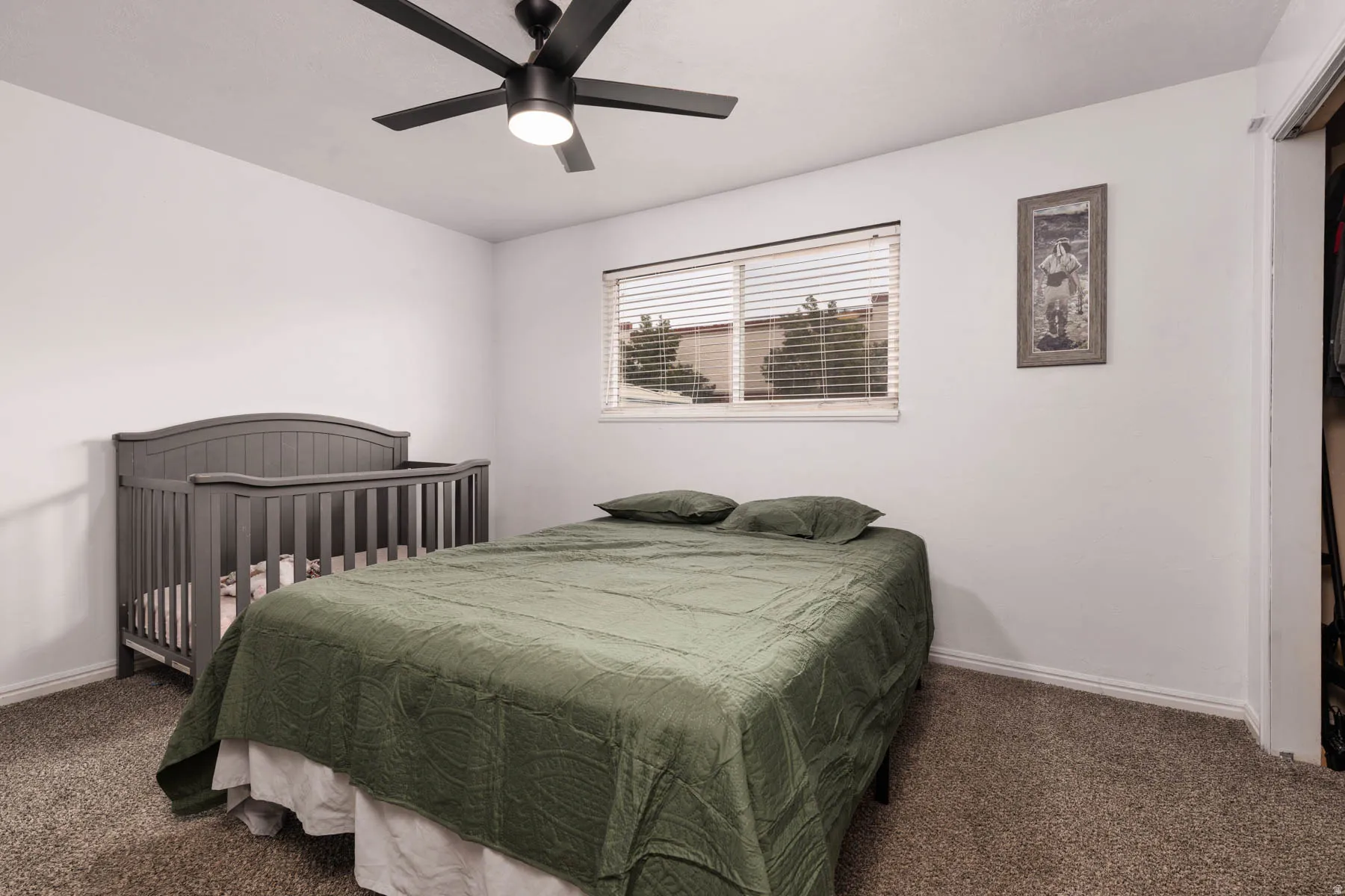 Bedroom featuring a window with horizontal blinds, a ceiling fan with integrated lighting, and neutral-toned walls