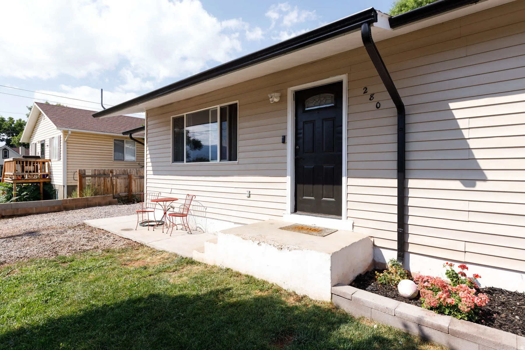 Cream-colored siding exterior featuring a black front door with decorative glass inlay