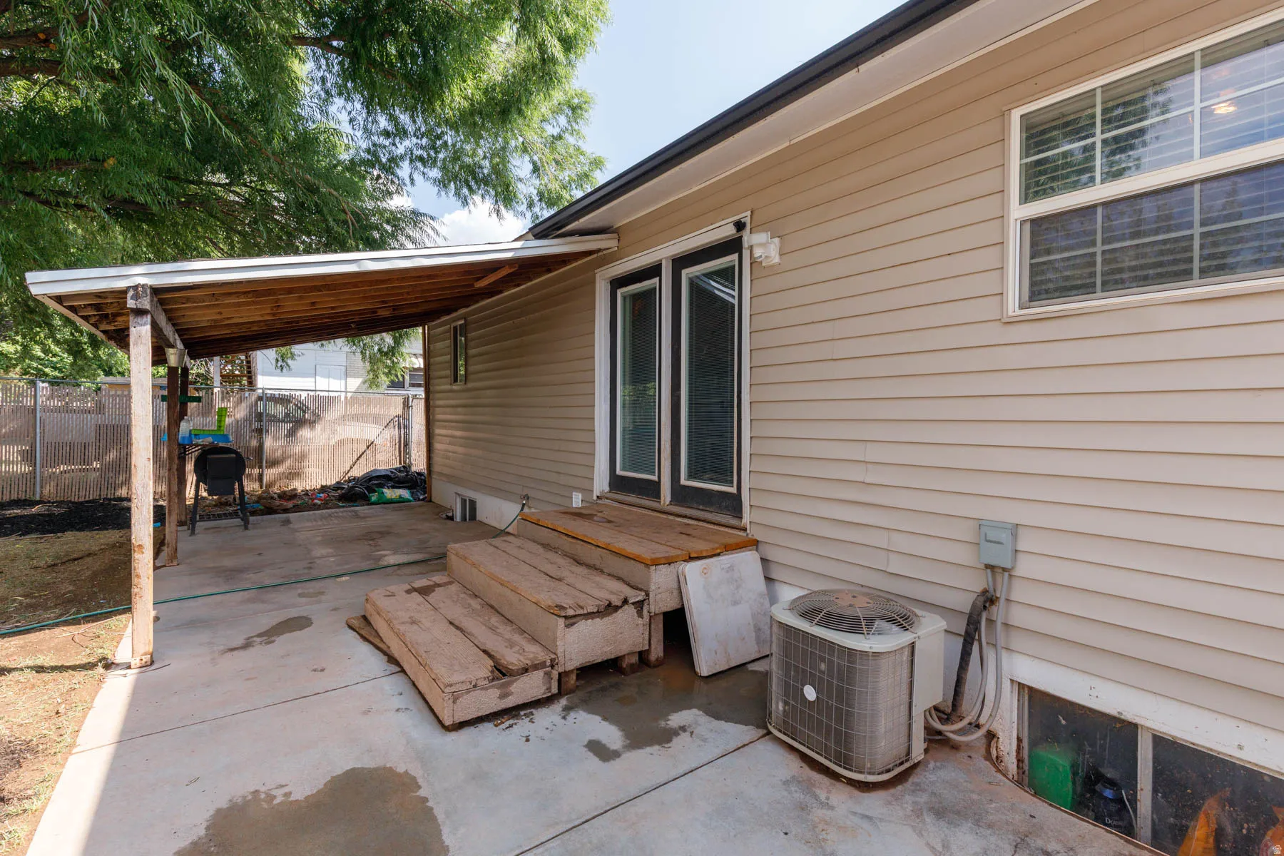 Exterior siding featuring a covered patio with a concrete slab, wooden support posts, and an exposed wood ceiling
