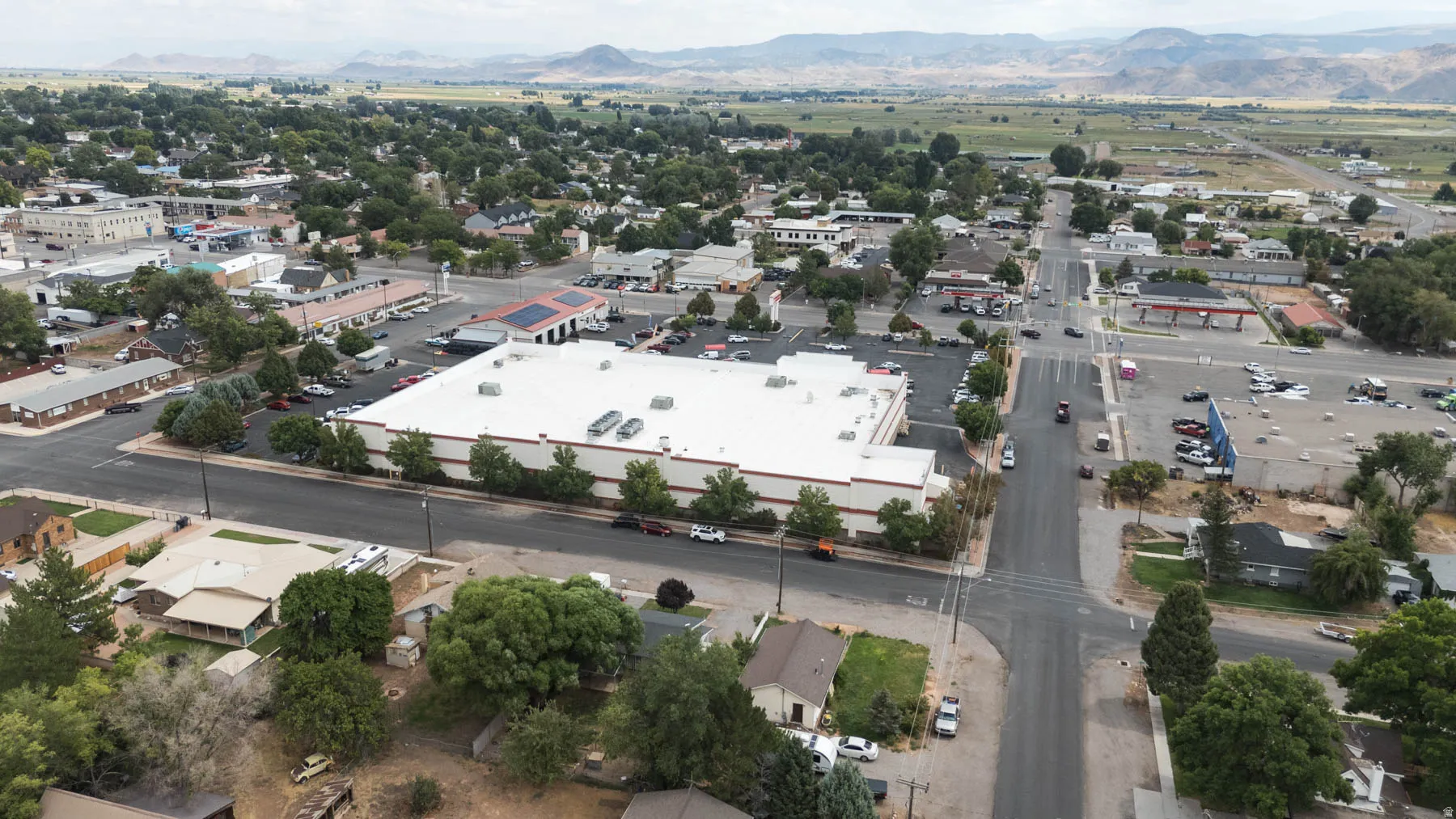 Commercial building with a white roof and extensive parking, situated on a corner lot
