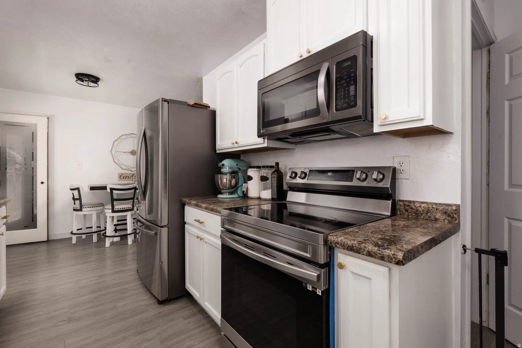 Modern kitchen featuring white cabinetry, stainless steel appliances, and wood-finish flooring