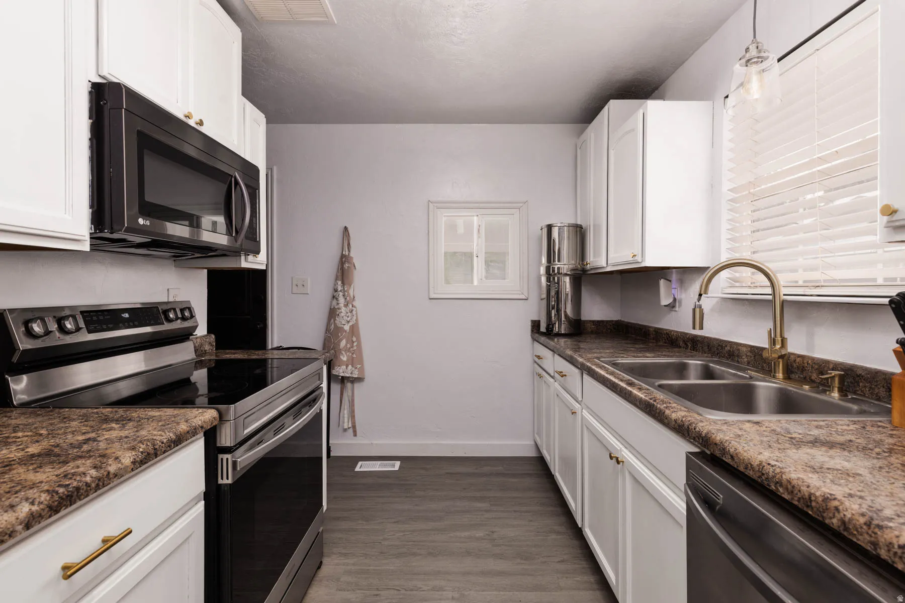 Kitchen featuring wood-finish flooring, white cabinetry with gold-tone hardware, and speckled countertops
