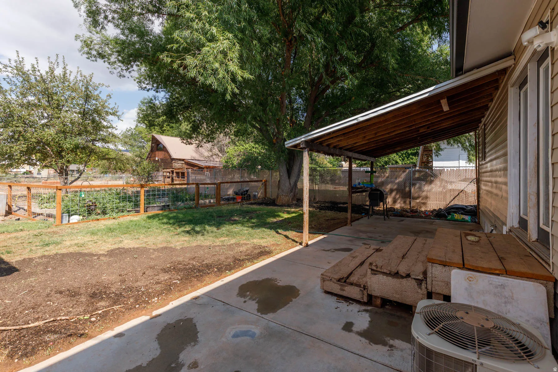 Backyard space featuring a covered patio, concrete slab, and a wood-slat fence