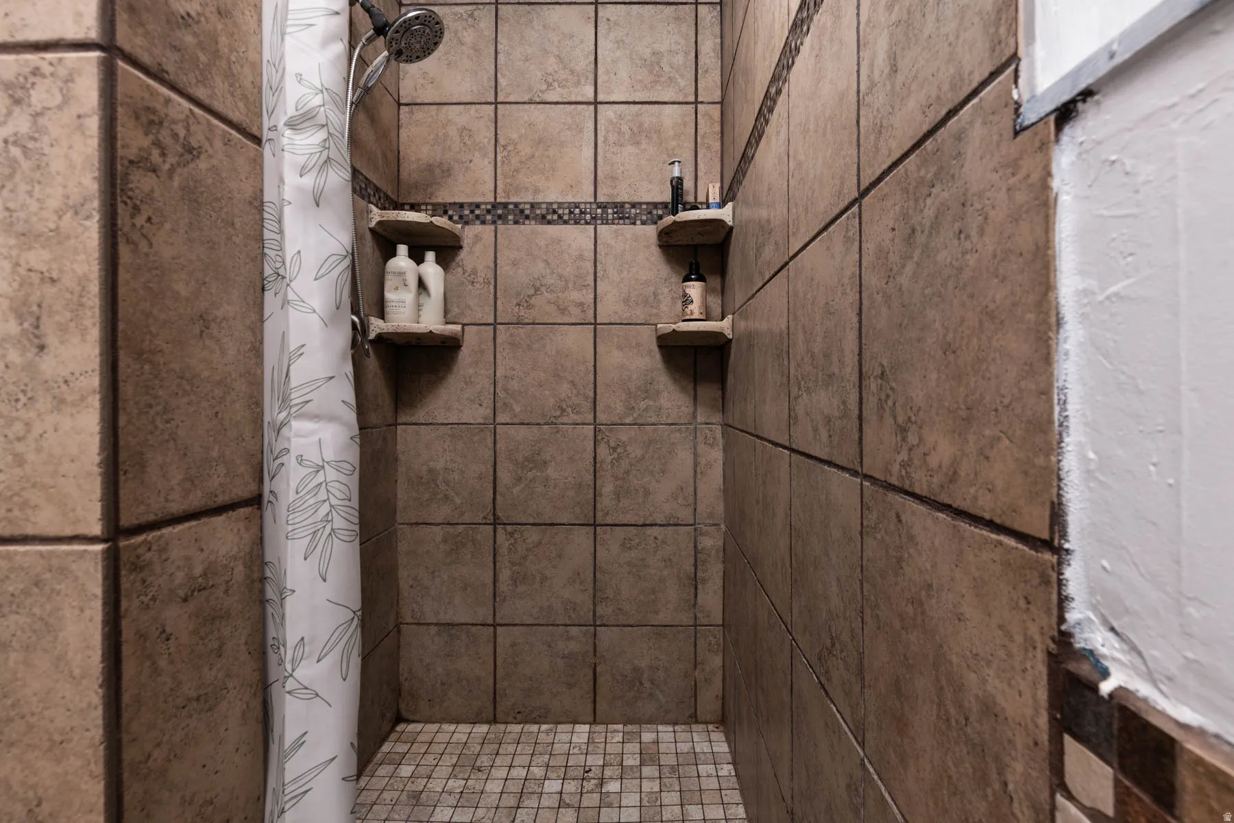 Tiled shower enclosure featuring a mosaic tile floor