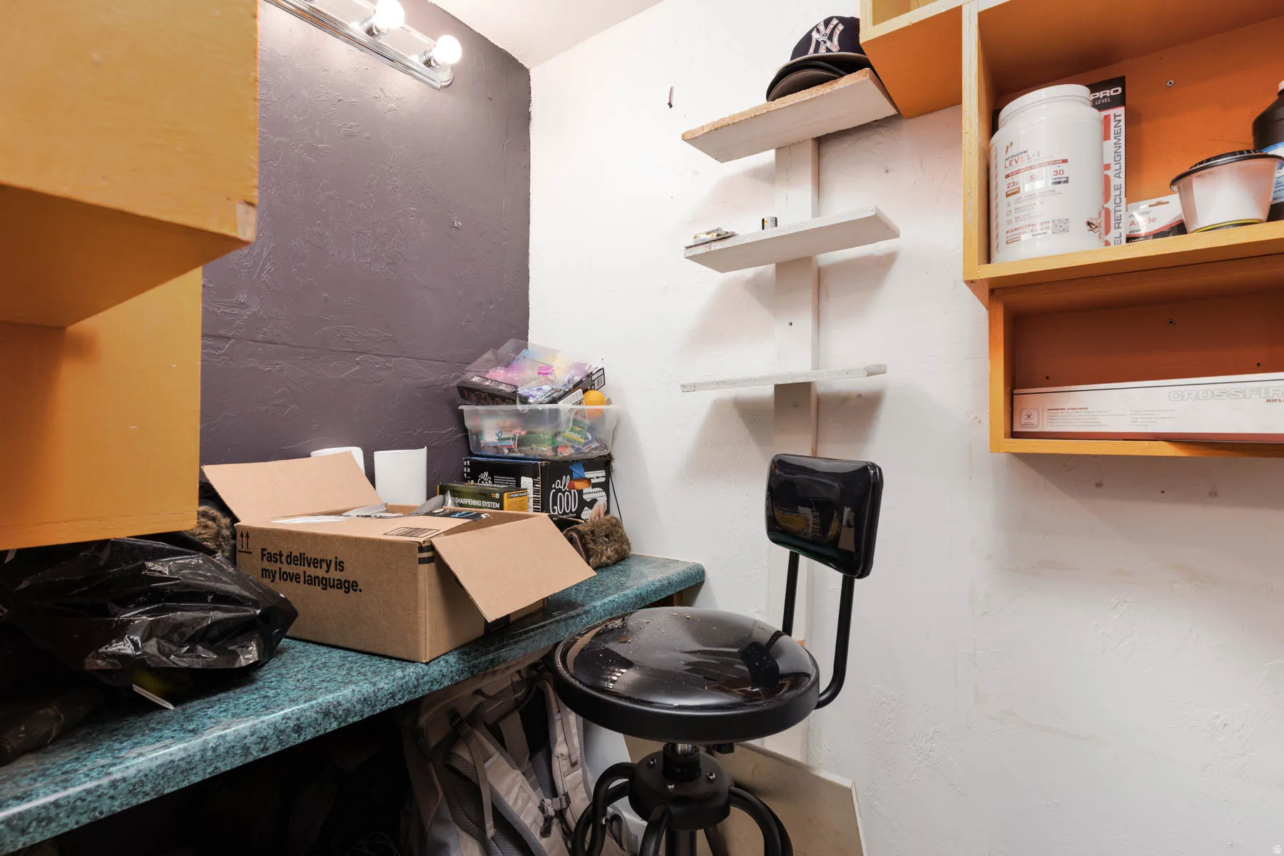 Work area featuring a green speckled countertop, wall-mounted shelving units, and a track light fixture