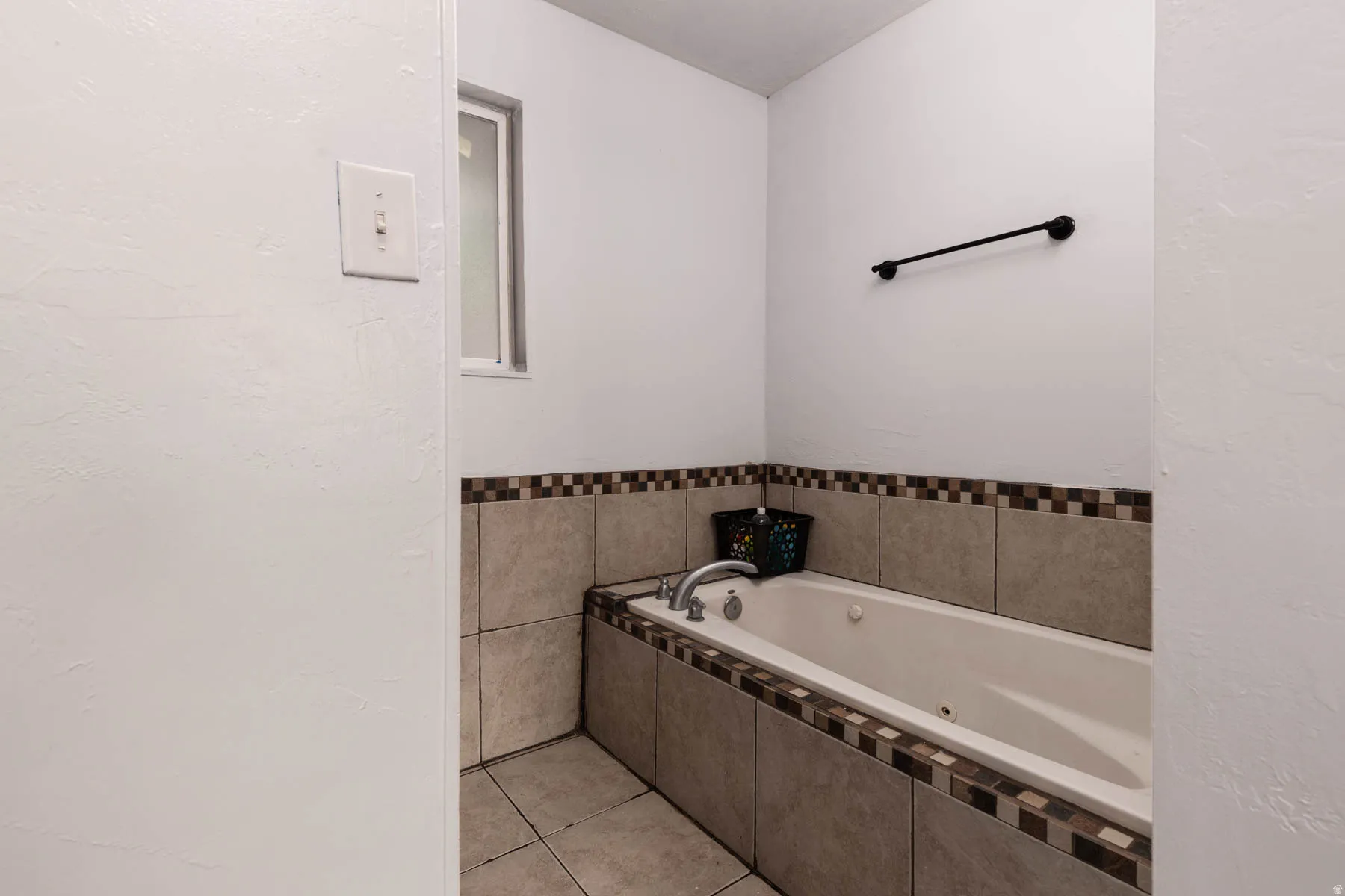 Built-in soaking tub featuring a tiled surround with a decorative mosaic border