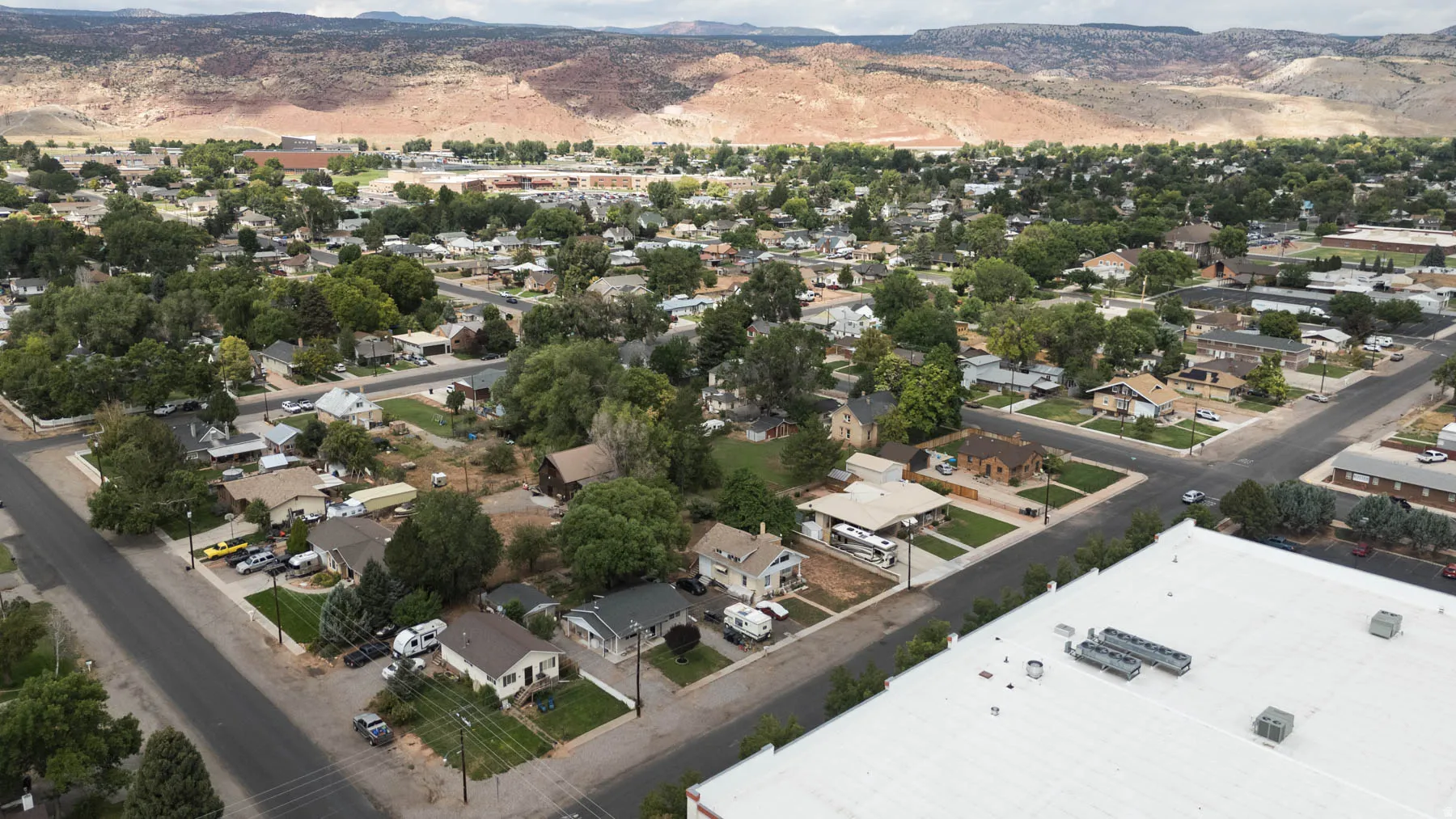 Aerial perspective showcasing a residential area with mature trees and mountain backdrop