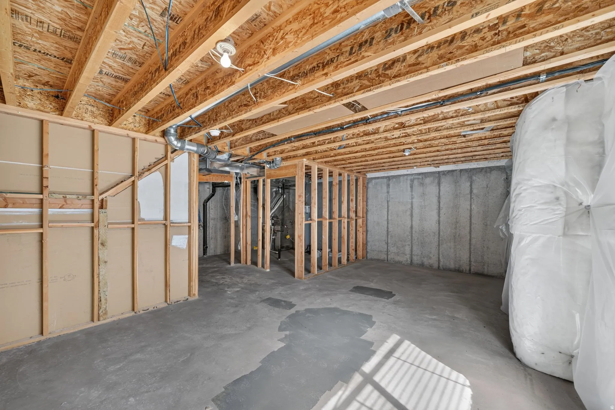 Unfinished basement space featuring exposed wood joists and concrete flooring