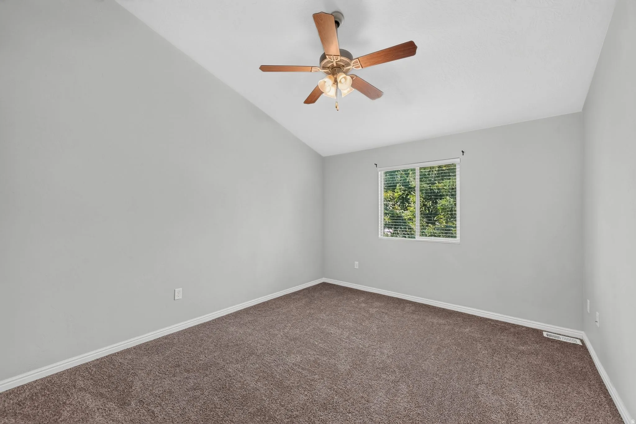 Room featuring vaulted ceilings, neutral wall tones, carpeted flooring, and a window with blinds