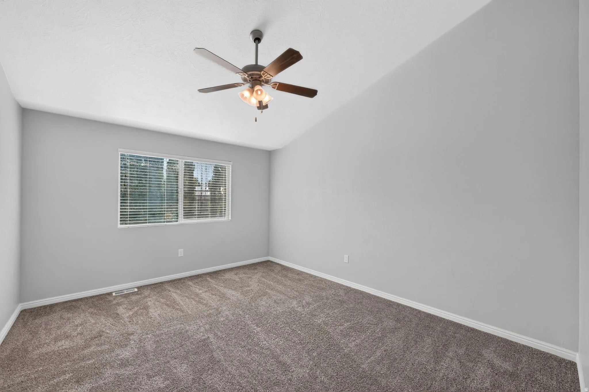 Vaulted ceiling with an integrated ceiling fan, carpeted flooring, window with blinds, and light gray painted walls