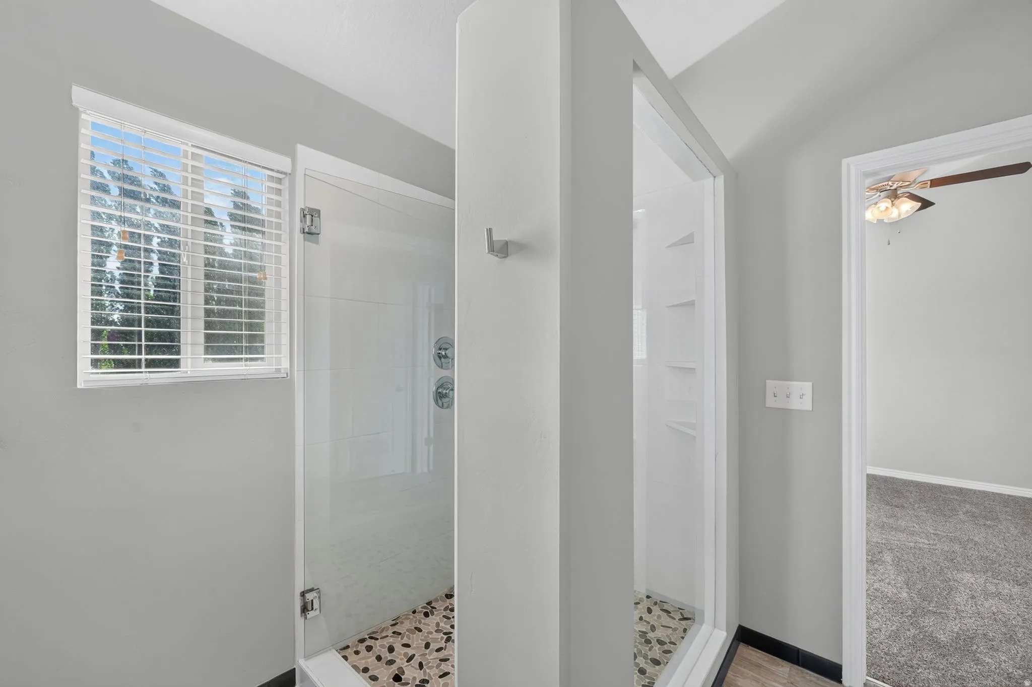 Dual glass-enclosed shower stalls featuring pebble-tile flooring and chrome fixtures
