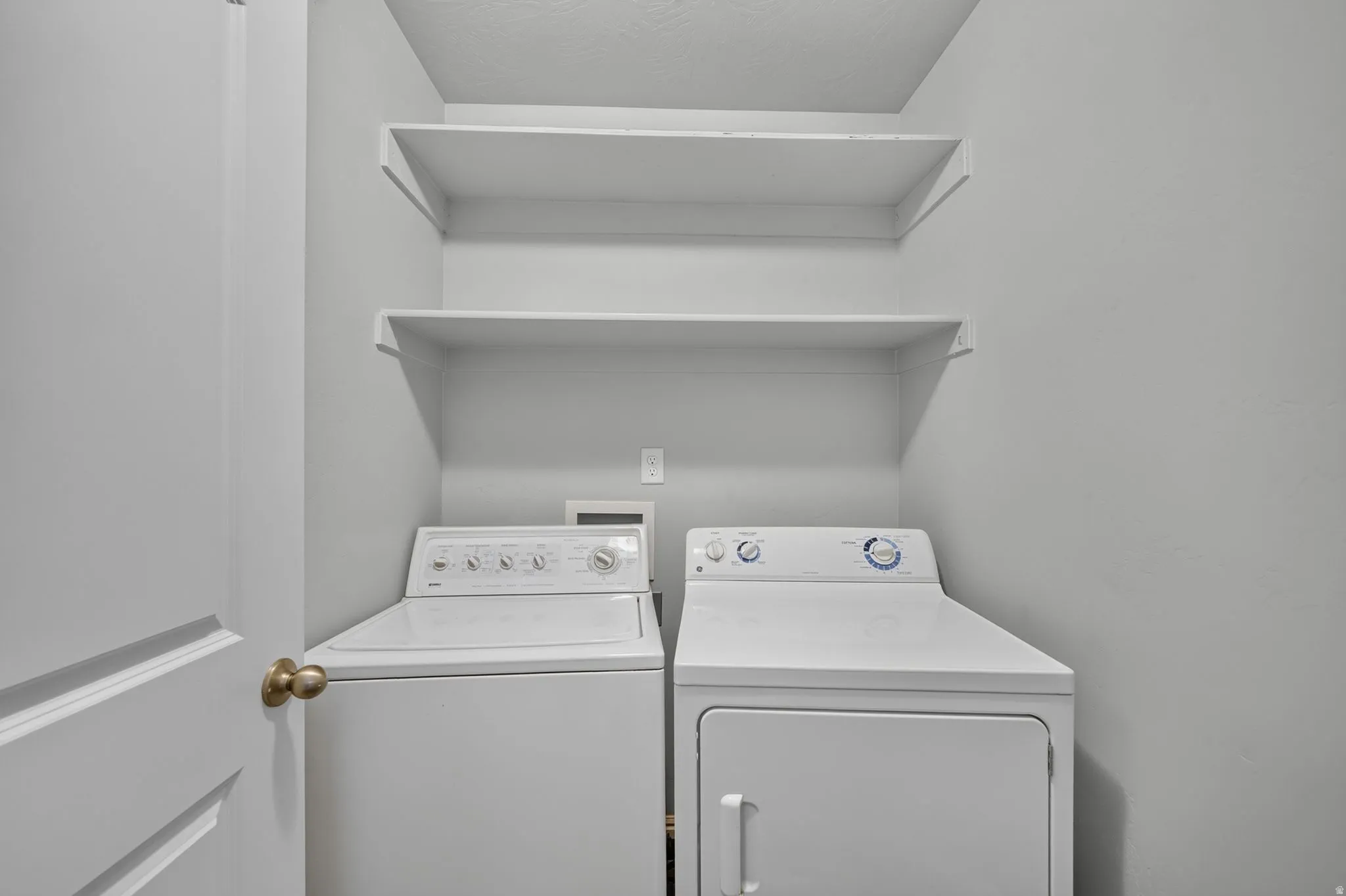 Dedicated laundry area featuring a washer and dryer, built-in shelving, and light gray wall paint