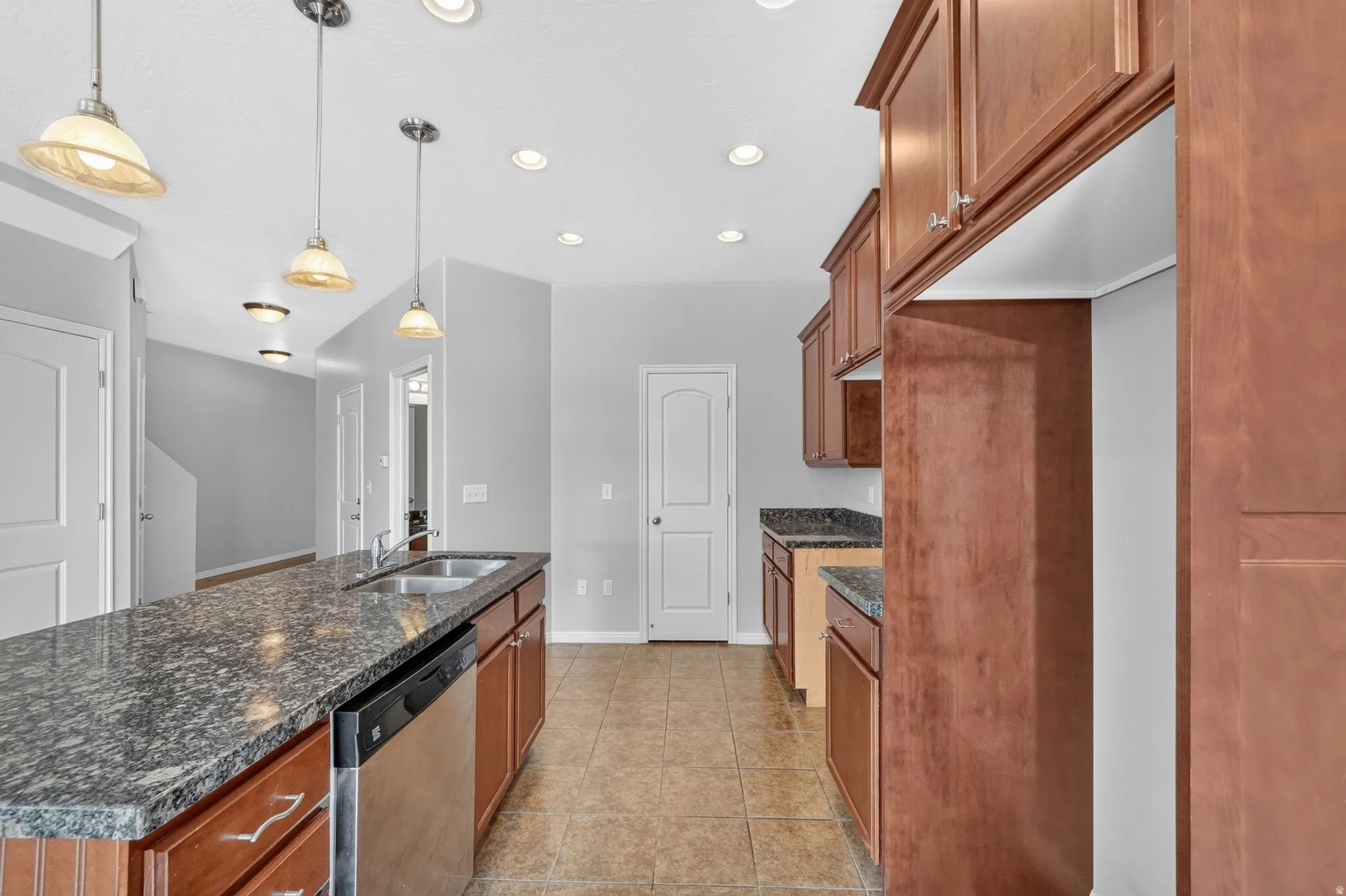 Kitchen featuring a central island with dual sinks, a stainless-steel dishwasher, and granite countertops