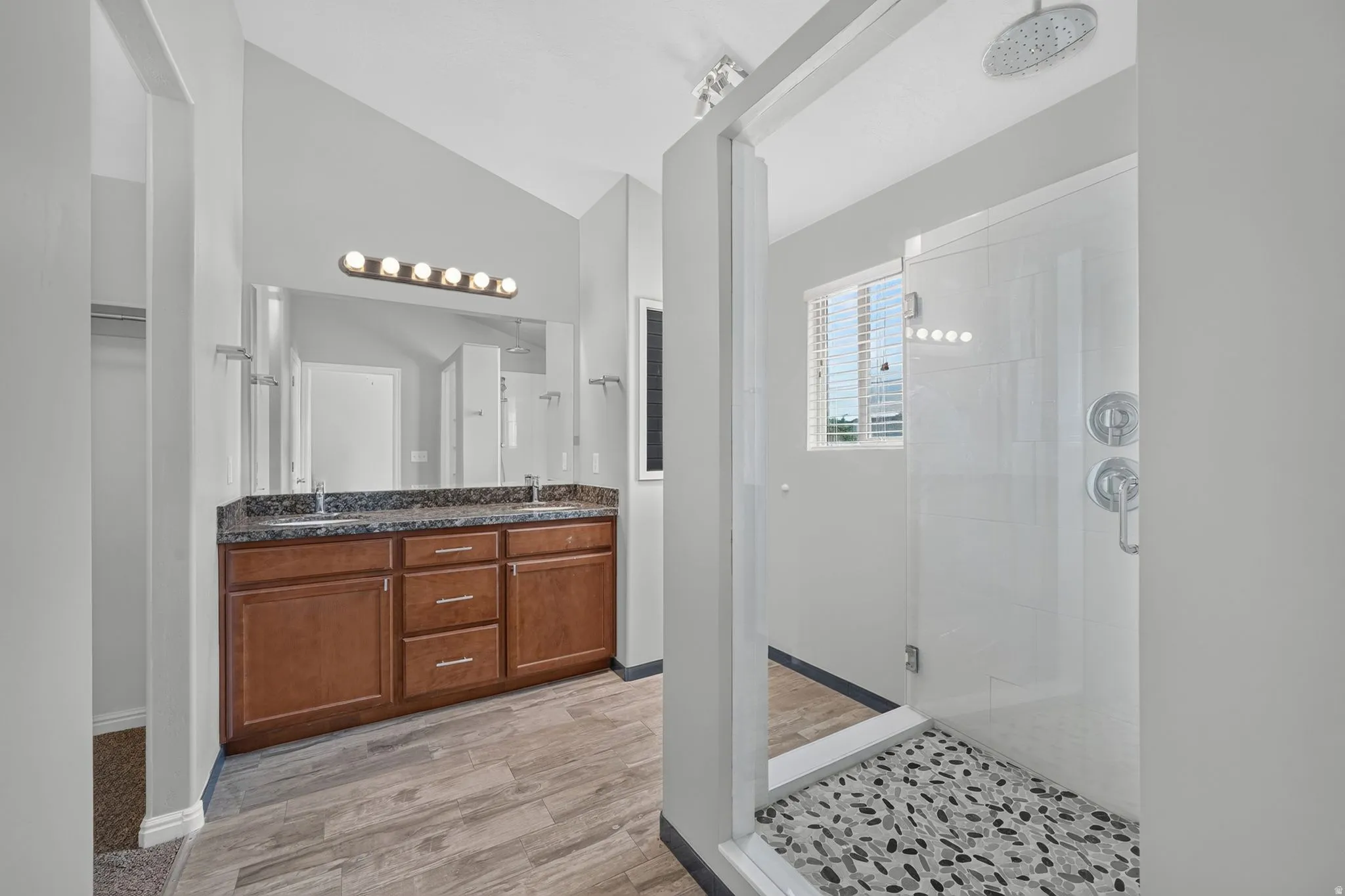 Spacious bathroom featuring a dual vanity with a dark countertop, wood-finish cabinetry, and a large mirror