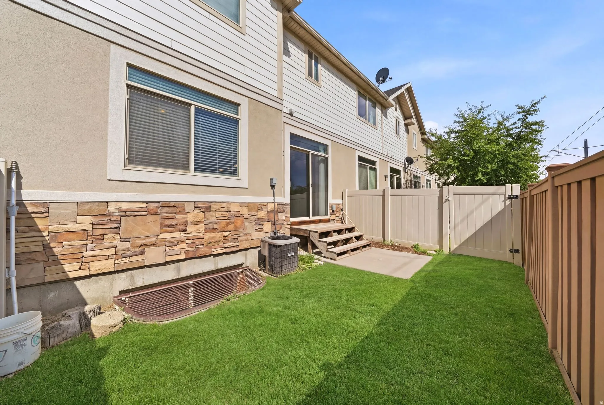 Private fenced yard featuring a grassy area, concrete patio, and mature tree