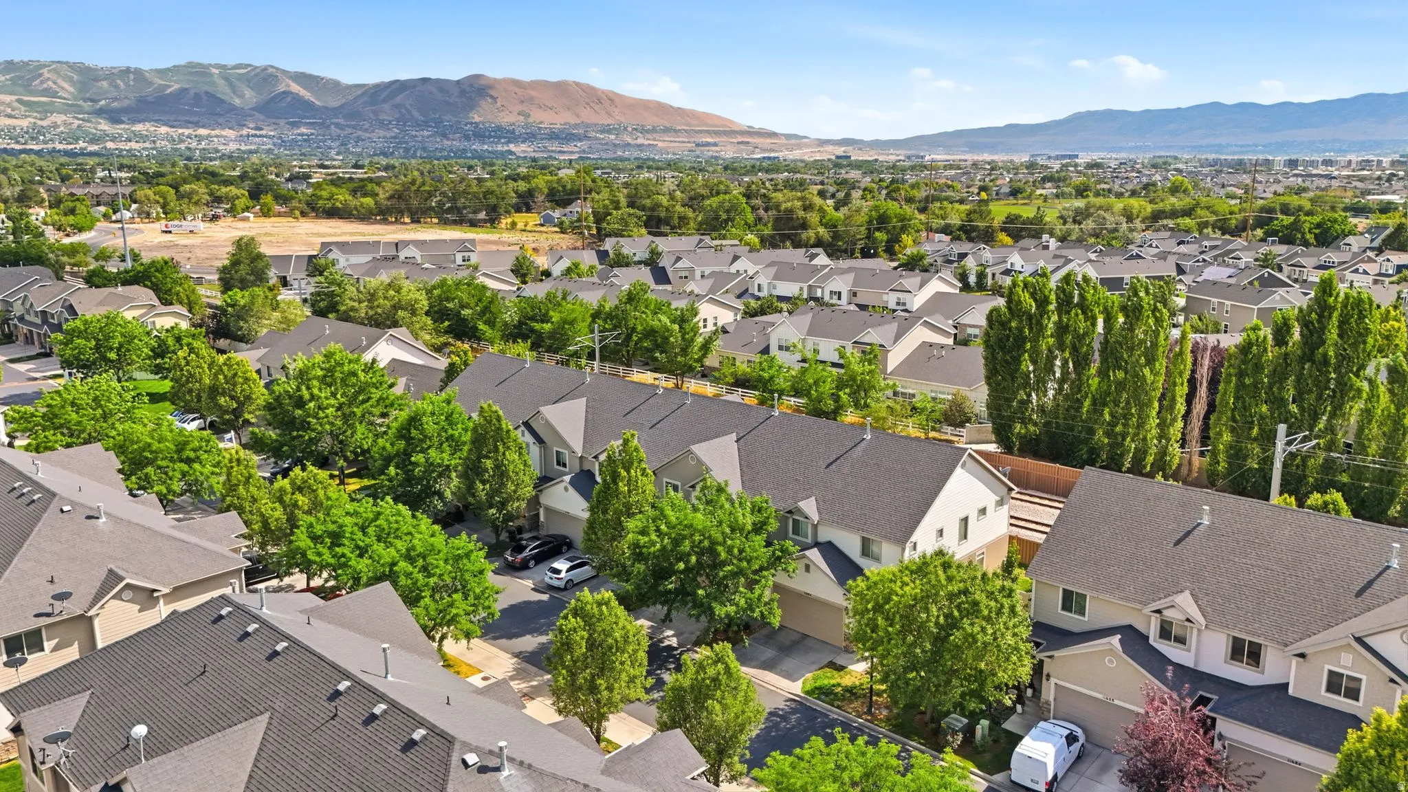 Aerial perspective showcasing a residential community with abundant mature trees and mountain backdrops