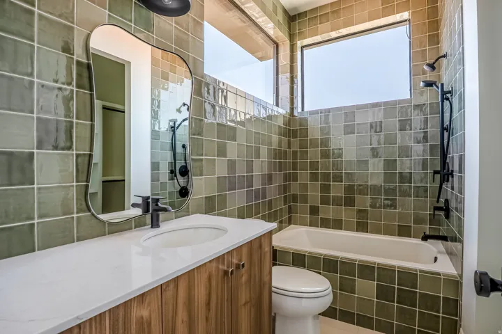 Spa-inspired bathroom featuring custom wood-finish vanity with white quartz countertop, matte black hardware, and vessel sink