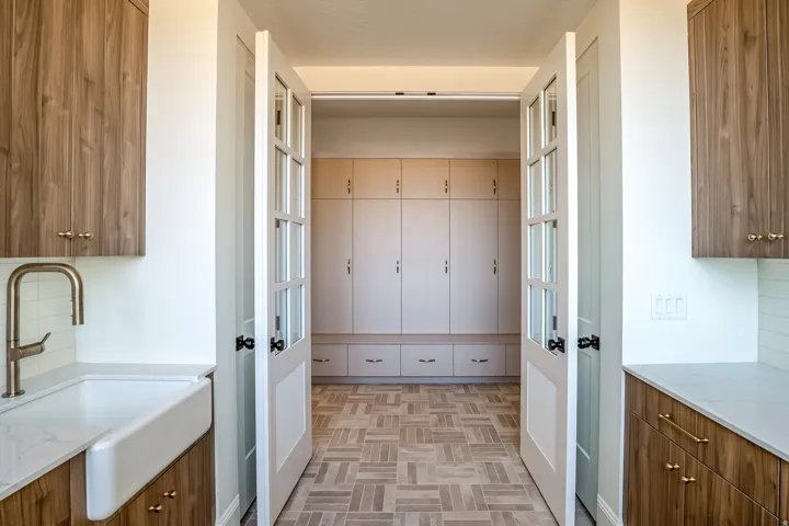 Wood-finish cabinetry, farmhouse sink, brushed gold hardware, shaker-style doors, and built-in storage
