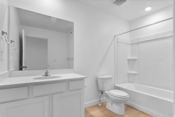 Bathroom featuring a white vanity with an integrated sink, polished chrome faucet, and a large wall-mounted mirror