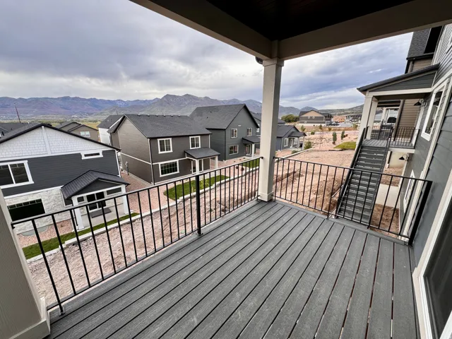 Exterior balcony with composite decking and black metal railing, featuring a covered ceiling and structural support column