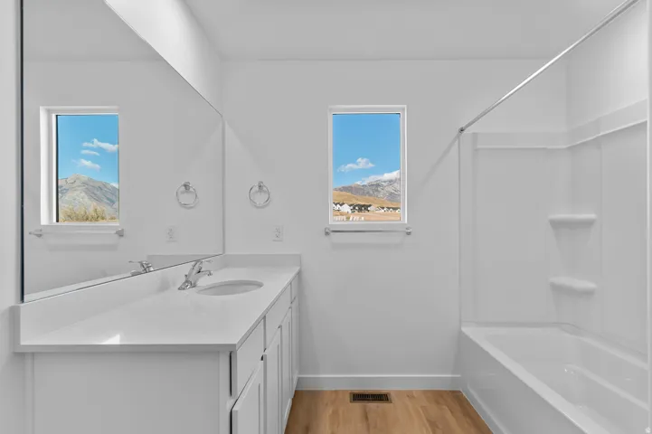 Bathroom featuring a white vanity with an integrated sink, polished chrome faucet, and expansive wall-mounted mirror