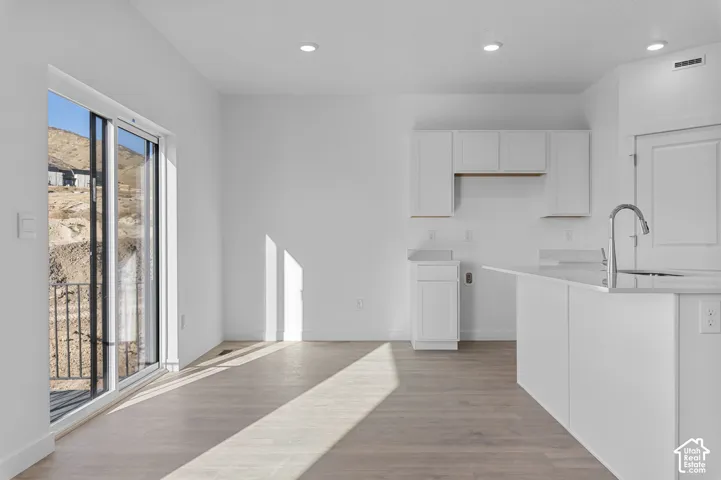 Open-concept living space featuring wood-finish flooring, recessed lighting, and a sliding glass door