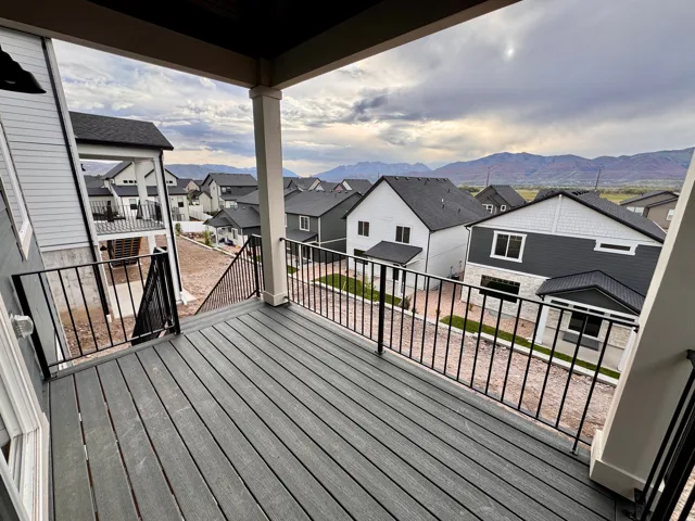 Outdoor deck with composite decking, black metal railings, and column supports, offering an expansive mountain backdrop