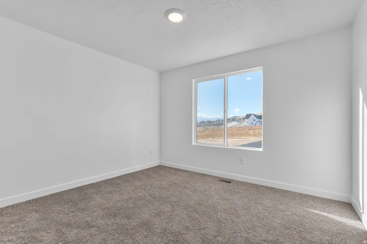 Bright room featuring a large window, recessed ceiling lighting, textured ceiling, white baseboards, and neutral carpet flooring