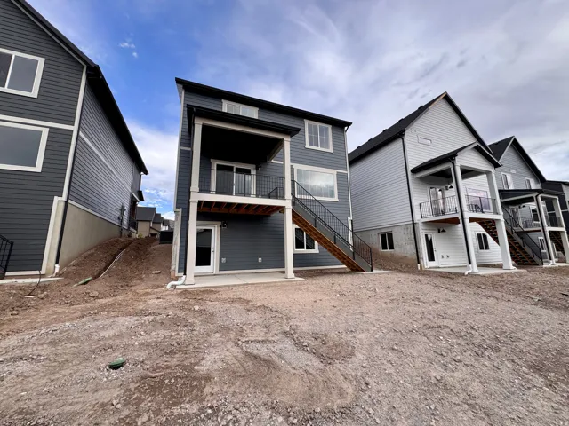 Two-story property featuring a covered balcony, lower-level patio, and exterior stairs with metal railings