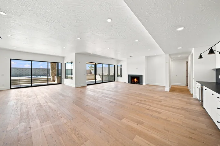 Expansive main living area featuring wood-finish flooring, a contemporary fireplace, and recessed lighting