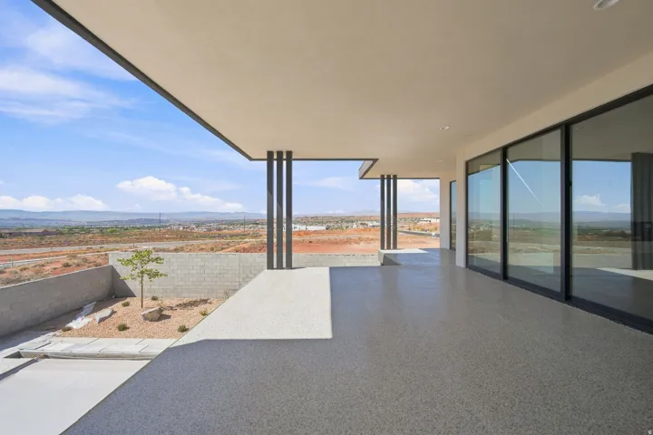 Expansive covered patio with a speckled concrete finish, supported by minimalist structural pillars
