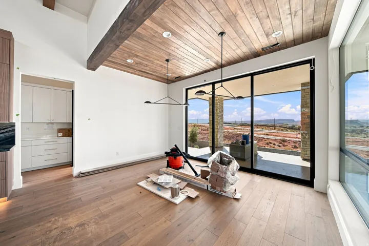 Wood-finish flooring, wood plank ceiling, exposed wood beams, modern lighting fixture, and a large sliding glass door
