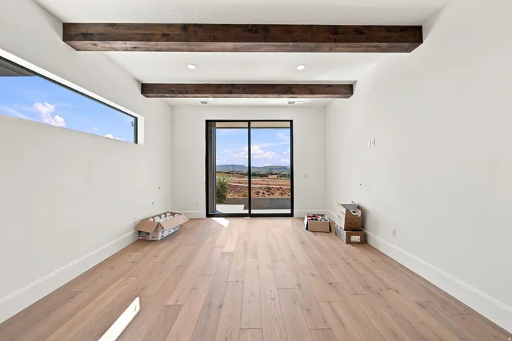 Wide plank wood-finish flooring with exposed ceiling beams and recessed lighting