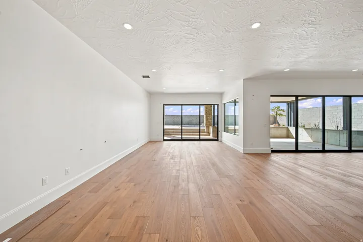 Expansive open-concept room featuring wood-finish flooring, white walls, and recessed lighting