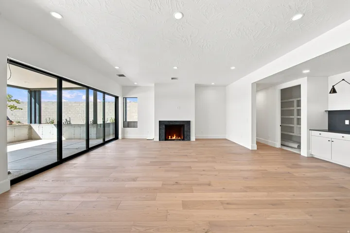 Wide plank wood-finish flooring, recessed lighting, and a modern fireplace with a dark surround