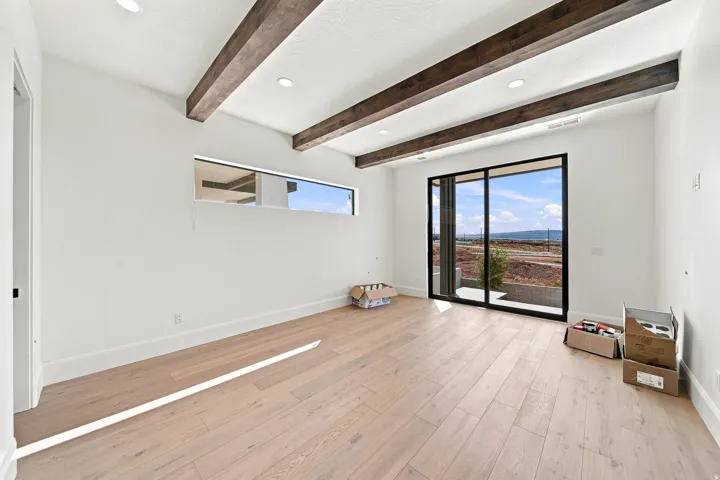 Room featuring exposed wood ceiling beams, recessed lighting, wood-finish flooring, a horizontal transom window, and a sliding glass door
