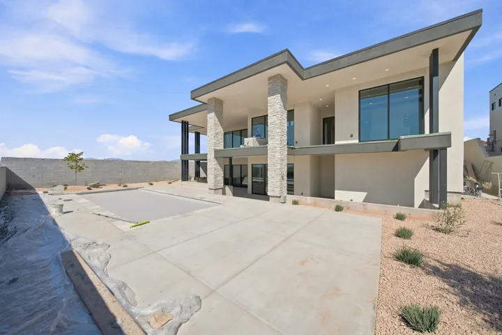 Contemporary multi-story exterior with stone veneer columns, expansive patio, integrated swimming pool, and large format windows
