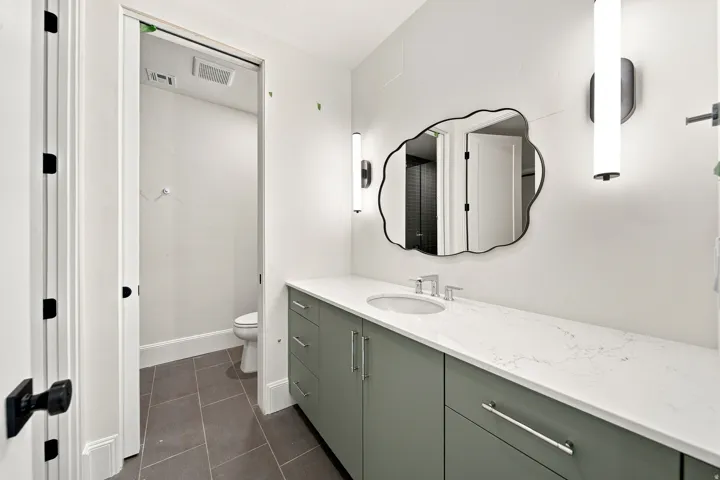 Extended vanity with light-toned countertop, integrated sink, and modern wall sconces