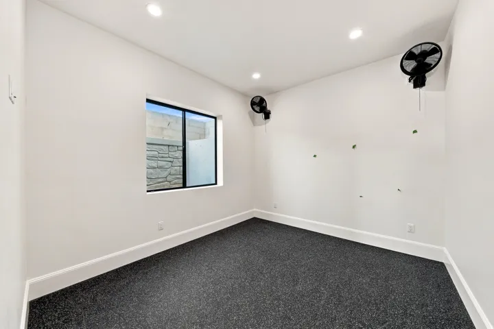 Recessed ceiling lighting, dark textured flooring, single window, white painted walls, and white trim