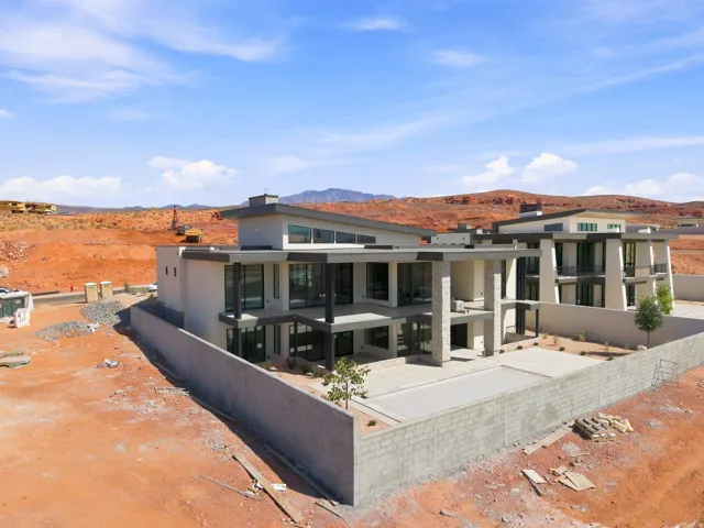 Modern architectural design featuring flat rooflines, extensive large-pane windows, multiple levels, and a concrete perimeter wall