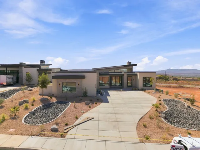 Contemporary exterior with an angled roofline, large format windows, a concrete driveway, and desert landscaping