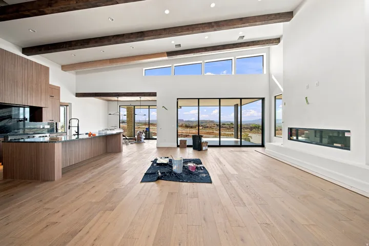 High-vaulted ceilings with exposed beams, wood-finish flooring, a linear fireplace, and large-format sliding glass doors
