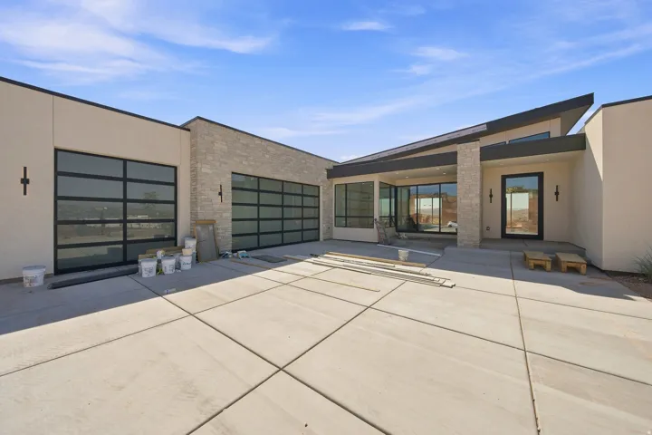 Contemporary exterior architecture featuring a prominent stone accent wall, stucco finishes, and a dark-framed entry door