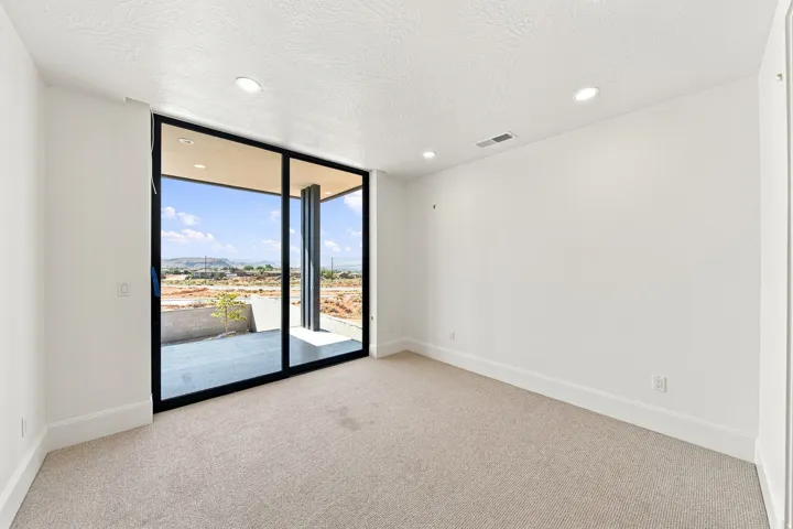 Wall-to-wall carpeting, recessed lighting, and a large sliding glass door opening to an outdoor patio