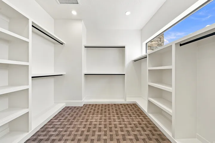 Custom closet system featuring built-in shelving, hanging rods, recessed lighting, and a panoramic window