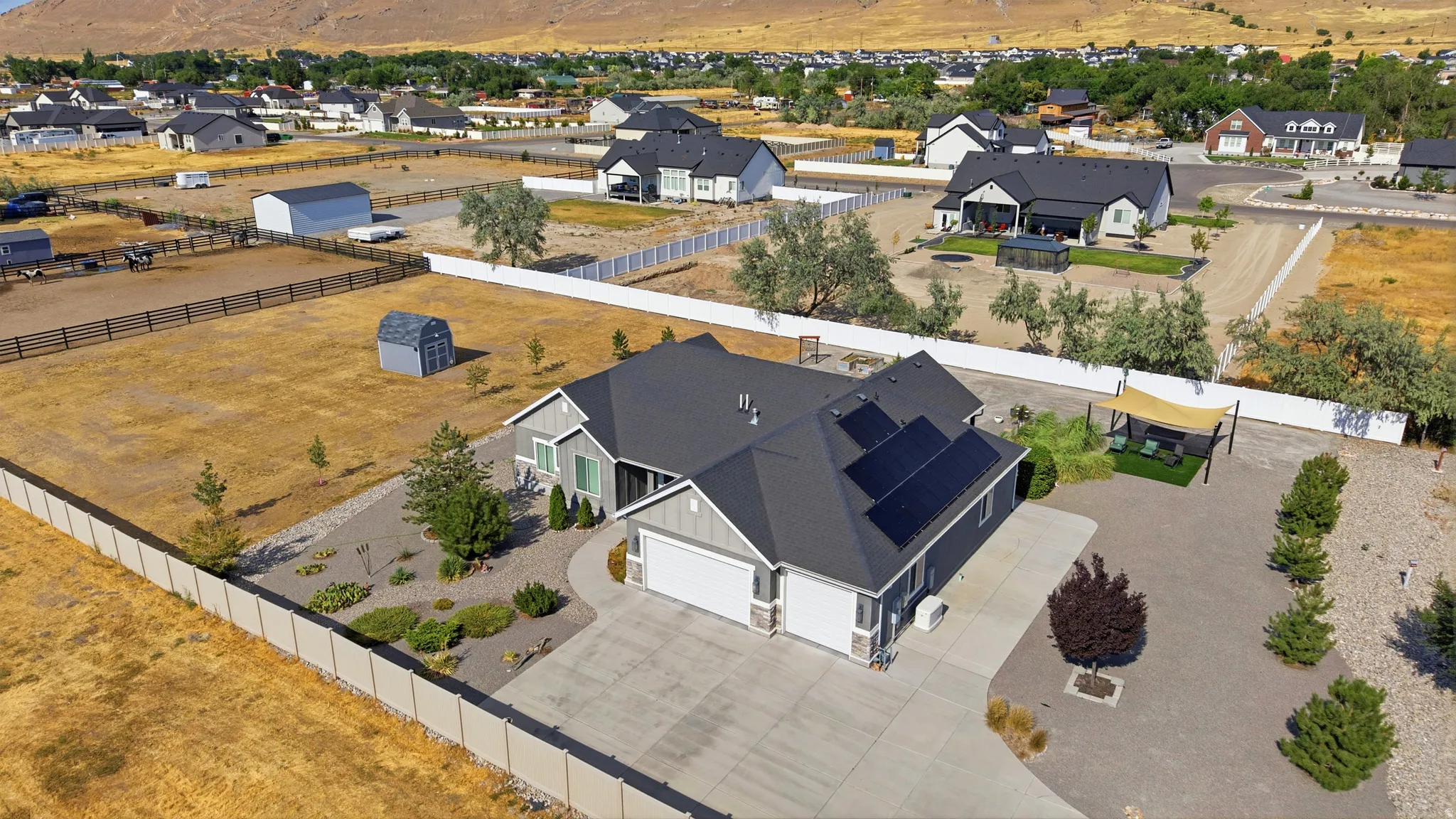 Contemporary residence with a dark shingle roof featuring solar panels, a two-car garage, and a concrete driveway